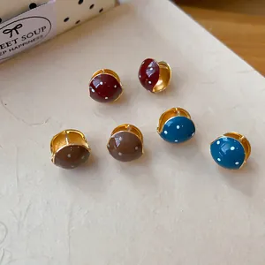 Detailed view of retro polka dot enamel huggie earrings in Maillard colors