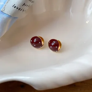 Close-up view of vintage Maillard red polka dot enamel hoop earrings on a shell dish
