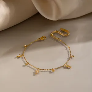 Detailopname van 18K vergulde roestvrijstalen armband met kruis- en zirkoonhangers.