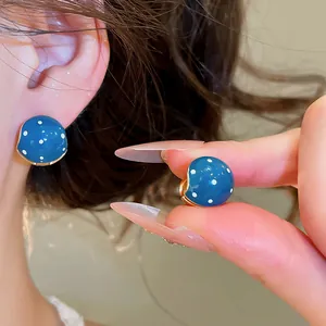Close-up detail view of vintage blue enamel polka dot stud earrings worn on the ear