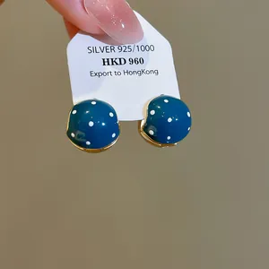 Macro view of retro blue enamel earrings with white polka dots on a silver display card