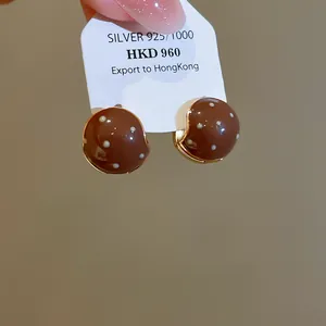 Detailed view of vintage brown enamel stud earrings with white polka dots on card