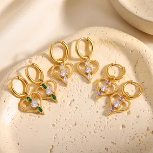 Nahaufnahme von herzförmigen goldenen Creolen mit grünen, weißen und lila Steinen