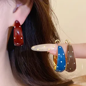 Close-up of vintage enamel polka dot hoop earrings in red blue and brown colors