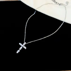 Primer plano de un collar con colgante de cruz de circón sobre fondo de terciopelo negro.