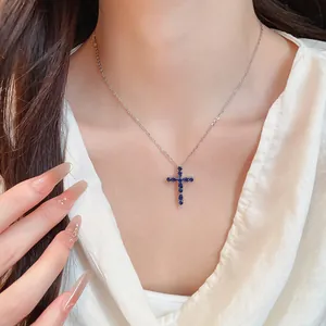 Detalle de collar con colgante de cruz chapado en oro 18k y circonitas azules finas.