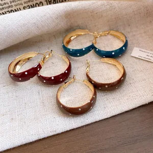 Macro view of retro enamel hoop earrings with white polka dots in various colors