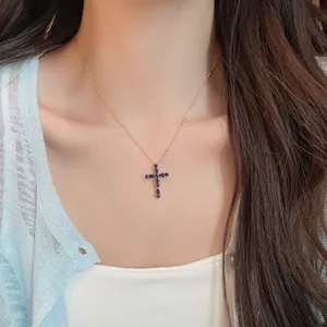 Primer plano de un collar con colgante de cruz en oro de 18k y circonitas azules