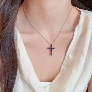 Primer plano de collar con colgante de cruz chapado en oro de 18k con circonitas azules