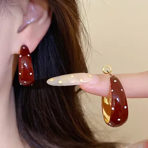 Close-up detail of retro brown enamel hoop earrings featuring a stylish white polka dot pattern.