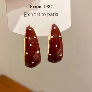 Detailed view of red oil-dripping hoop earrings with white polka dots and retro C-shape design