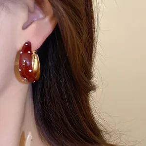 Close-up of vintage-style burgundy hoop earrings with white polka dots on model