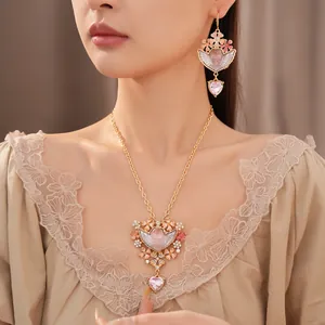 Set di gioielli stile palazzo con ciondoli angelo e cuori rosa indossati da una modella.