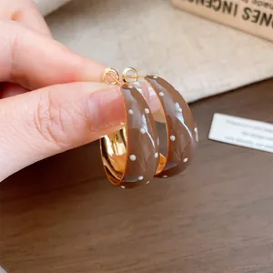 Detailed close-up of brown enamel hoop earrings with vintage white polka dot design
