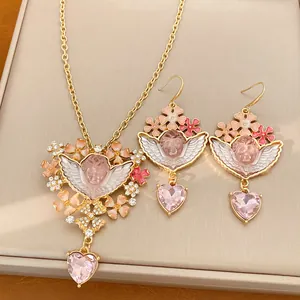 Set gioielli angelo e cuore vintage con dettagli floreali rosa e cristalli lucenti.