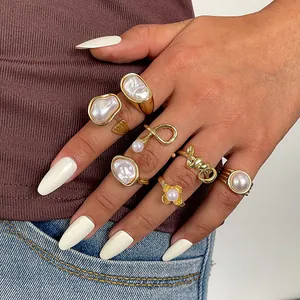 Close-up of 7-piece vintage gold ring set with irregular pearls and floral motifs