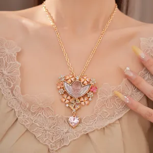 Dettaglio della collana con ciondolo angelo vintage ornata da fiori rosa e strass luccicanti