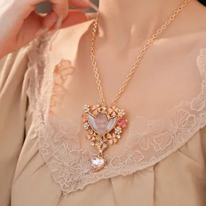 Primo piano della collana con angelo vintage in resina rosa e strass floreali.
