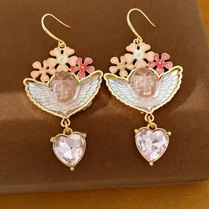 Dettaglio di orecchini vintage con angelo, cristalli a cuore rosa e fiori in smalto