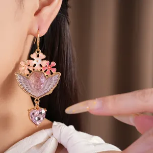 Dettaglio orecchini vintage con fiore rosa, angelo in resina e cristallo a cuore