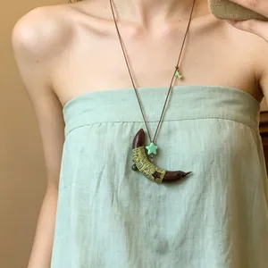 Detailopname van de etnische ketting met maanvormige houten hanger en groene draad