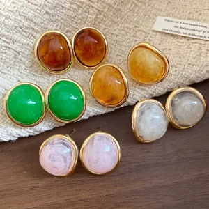 Close-up of vintage resin oval stud earrings with gold-tone borders and marble texture
