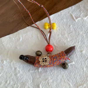 Detailopname van handgemaakte houten ketting in etnische stijl met gekleurde touwtjes en bel