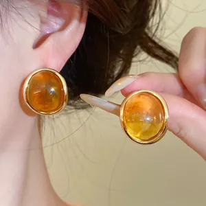Close-up view of elegant vintage amber resin stud earrings featuring a polished gold-plated rim