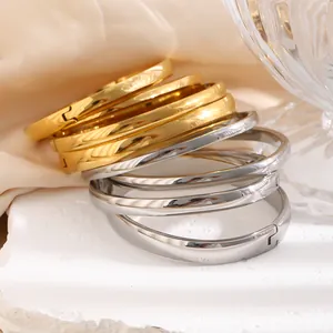 Nahaufnahme von gestapelten polierten Gold- und Silber-Edelstahl-Minimalarmreifen mit Verschluss