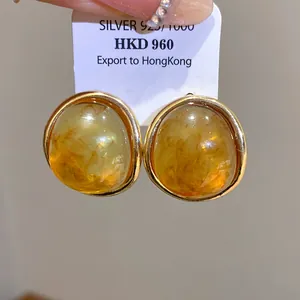 Close-up detail of vintage amber resin oval stud earrings with elegant gold-tone metal frames