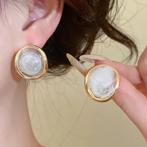 Detail view of vintage resin oval stud earrings with elegant gold frame on Asian model ear