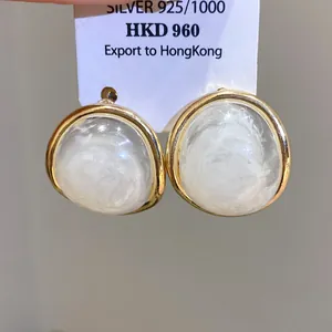 Macro detail of vintage oval resin earrings with gold trim on a white display card