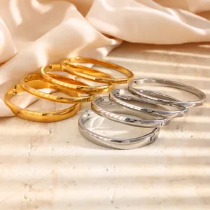 Nahaufnahme von minimalistischen Edelstahl-Armreifen in Gold und Silber auf eleganter Seide