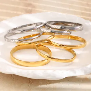 Elegante Detailansicht stapelbarer Armreifen aus Titanstahl in Gold und Silber