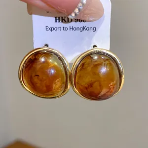 Close-up of vintage Maillard style resin oval stud earrings with gold-toned edges.