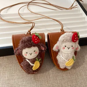 Vista dettagliata di simpatici ciondoli a forma di pecora di peluche con pochette in pelle.