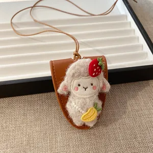 Dettaglio di un ciondolo a forma di pecora di peluche con ricami su base in pelle