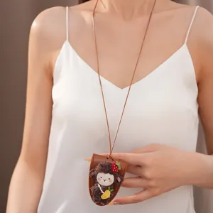 Dettaglio della collana con ciondolo a scimmia di peluche su base in pelle.