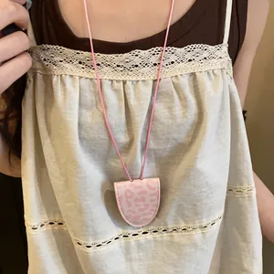 Gros plan d'un collier pince à lunettes imprimé léopard rose porté sur un haut vintage
