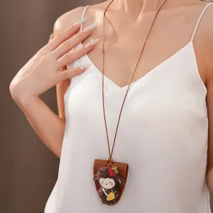 Dettaglio di un ciondolo a scimmia di peluche su una collana portaocchiali in pelle.