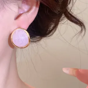 Close-up detail shot of a vintage pink marble resin stud earring with gold-toned metal rim