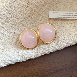 Close-up detail of vintage pink resin oval stud earrings with elegant gold-tone rim