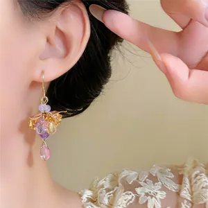 Primo piano dettagliato di orecchini a fiore vintage con nappe a goccia viola e oro