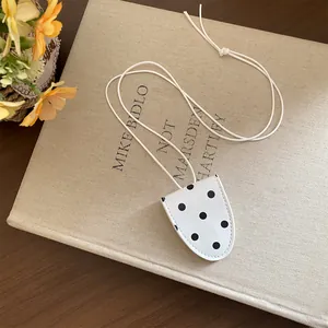 Détail d'un collier porte-lunettes vintage à pois blancs et noirs posé sur un livre ancien.