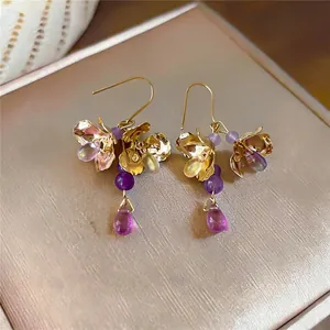 Primo piano di orecchini floreali vintage con perle viola e ganci dorati a goccia