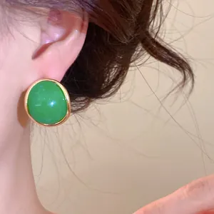 Close-up detail of retro green resin oval stud earring with golden frame shown on model