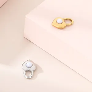 Primo piano di ciondoli a forma di lucchetto a cuore in oro e argento con inserti in perle.
