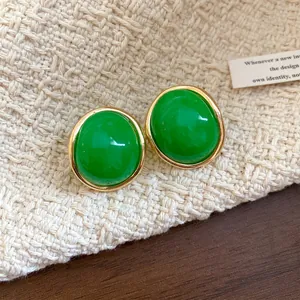 Close-up detail of retro green resin oval stud earrings with elegant gold-tone borders