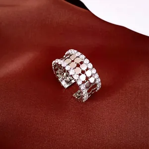 Detailopname van een zilverkleurige open ring met zeshoekig patroon en steentjes.
