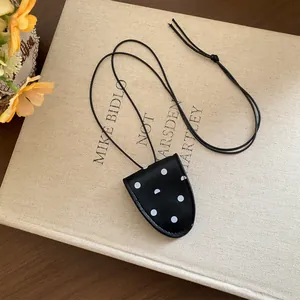 Collier pendentif vintage à pois avec cordon noir posé sur un livre beige texturé